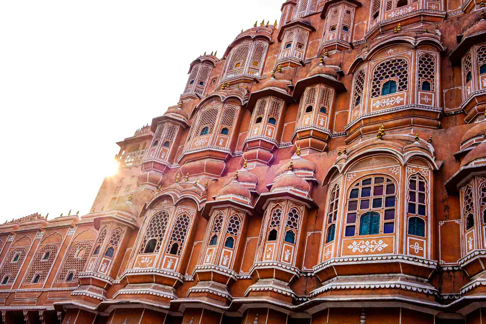 Sun flaring across the pink honeycomb facade of the Hawa Mahal