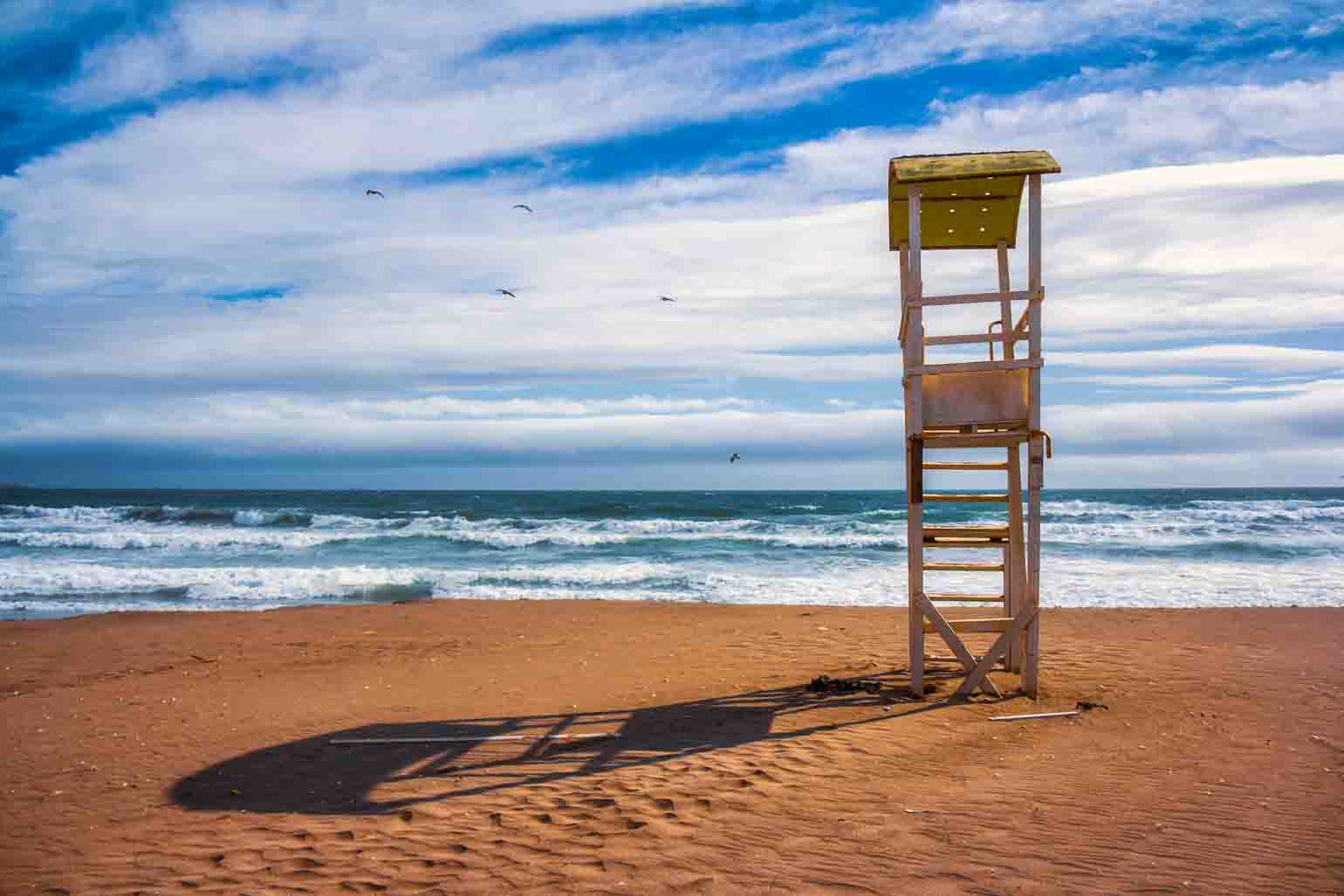 A single lifeguard chair on an empty stretch of beach