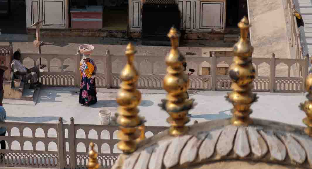 Woman balancing a basket on her head as she crosses a temple courtyard