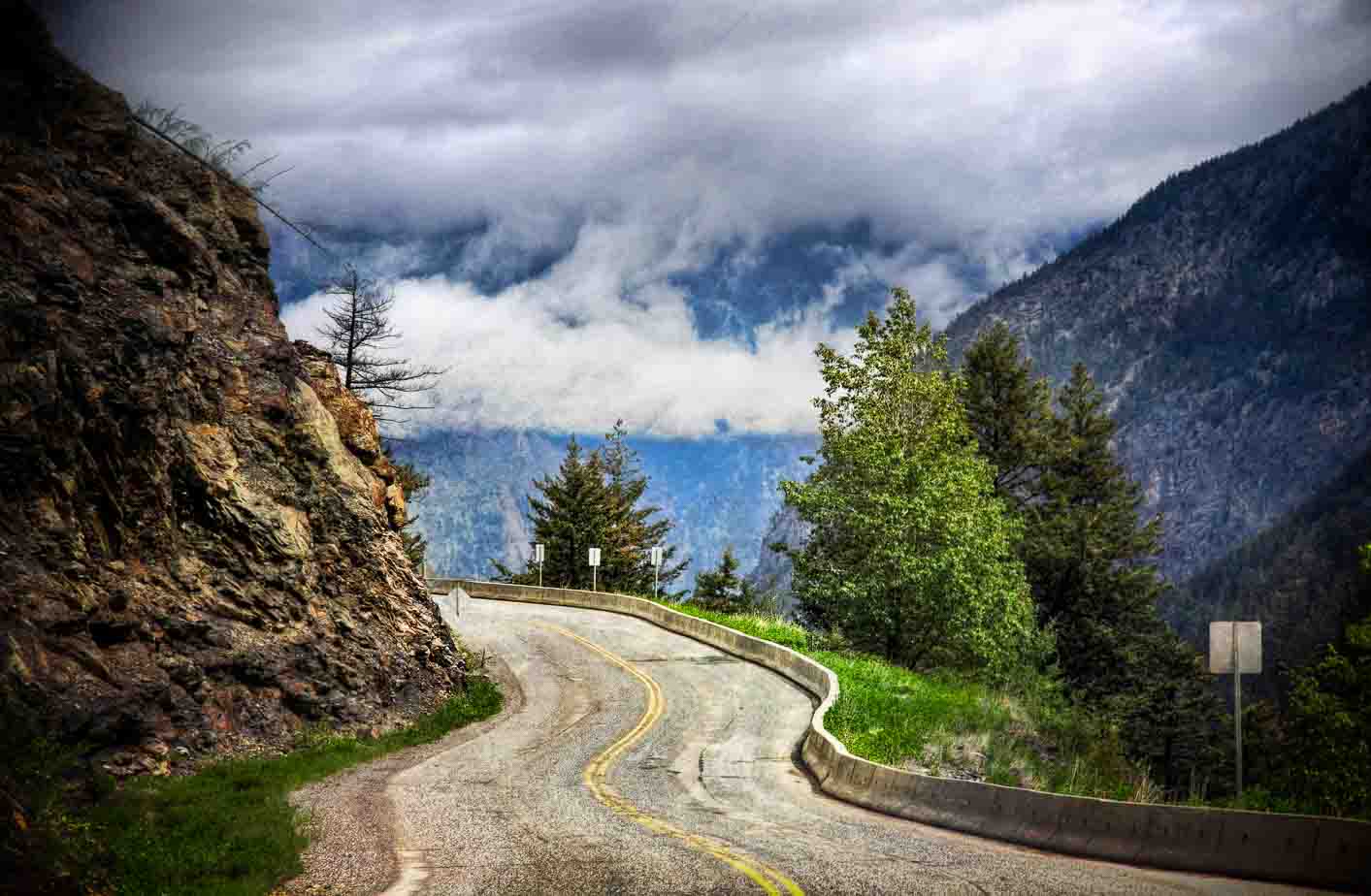 A winding mountain road under dramatic clouds