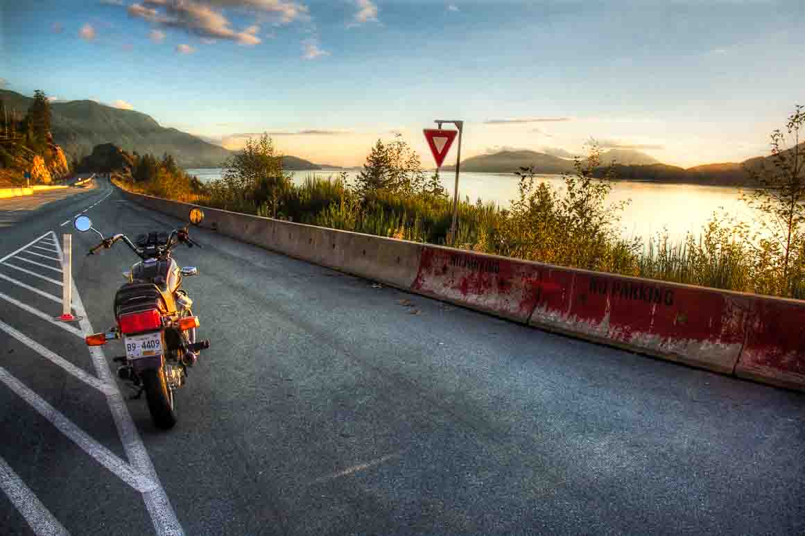 Parked motorbike on the shoulder of a coastal highway at golden hour