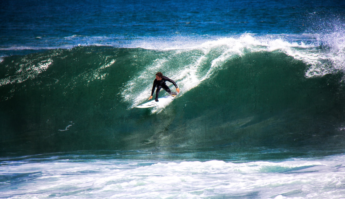 A surfer dropping into a clean turquoise wave off the coast at Arica.